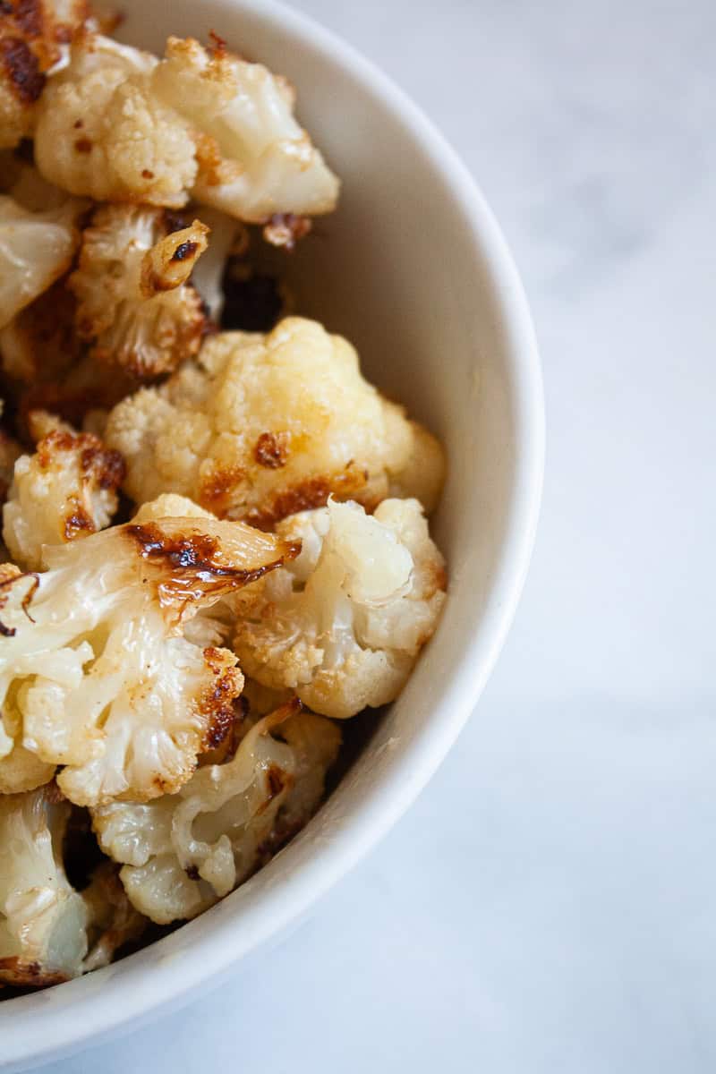 A close up of half a bowl of roasted cauliflower.