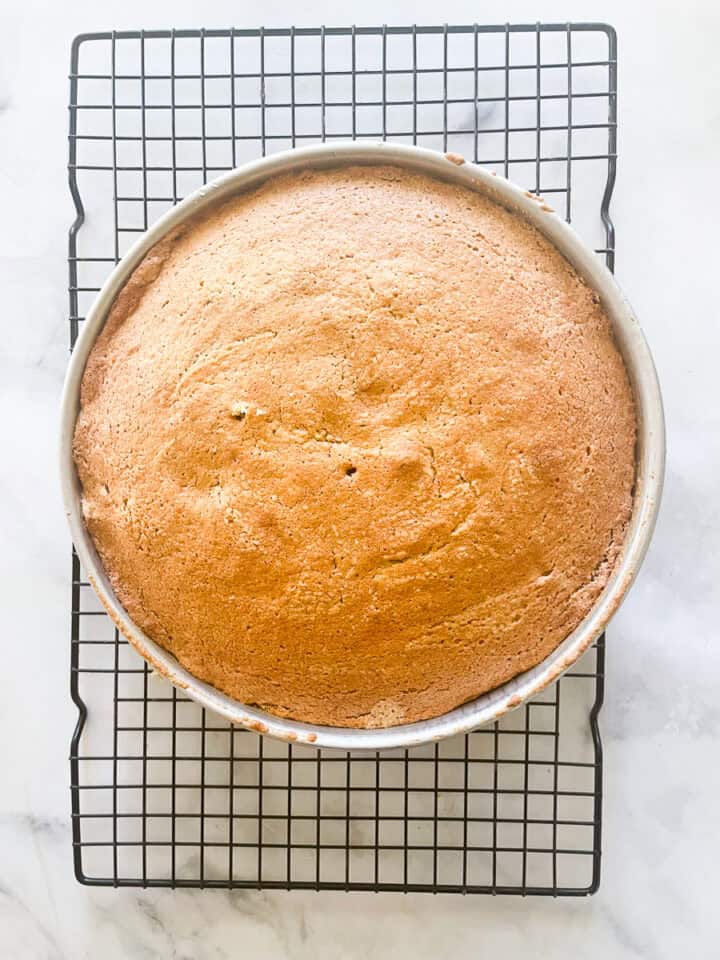 The oat flour vanilla cake cools in the pan on a rack.
