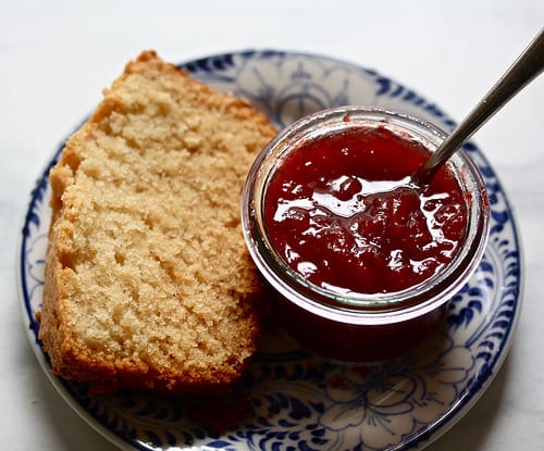 A piece of vanilla honey tea cake and strawberry jam on a plate.
