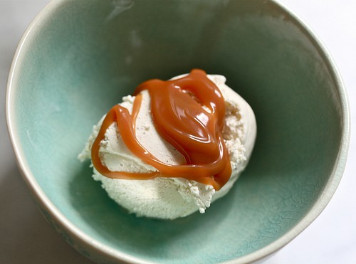 A scoop of vanilla ice cream topped with homemade caramel sauce.