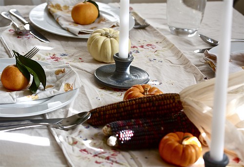 A view of the thanksgiving table with taper candles and mini corn.