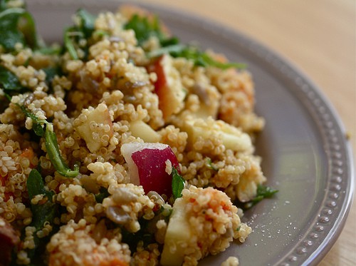 A close up of a plate of quinoa salad with apples and vegetables.