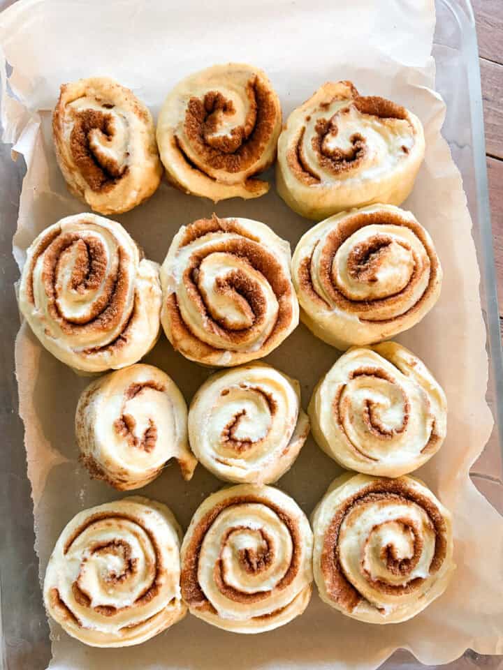 My homemade sticky buns recipe is make-ahead friendly and amazingly good! A thick maple syrup topping turns these into a bakery-worthy treat. Sticky buns after being rolled up.