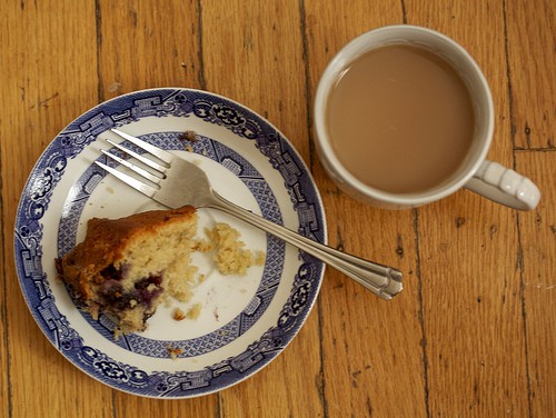 Blueberry coffee cake on a plate with a cup of coffee.