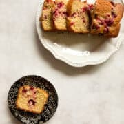 A sliced loaf of lemon cranberry bread and a slice of bread on a plate.