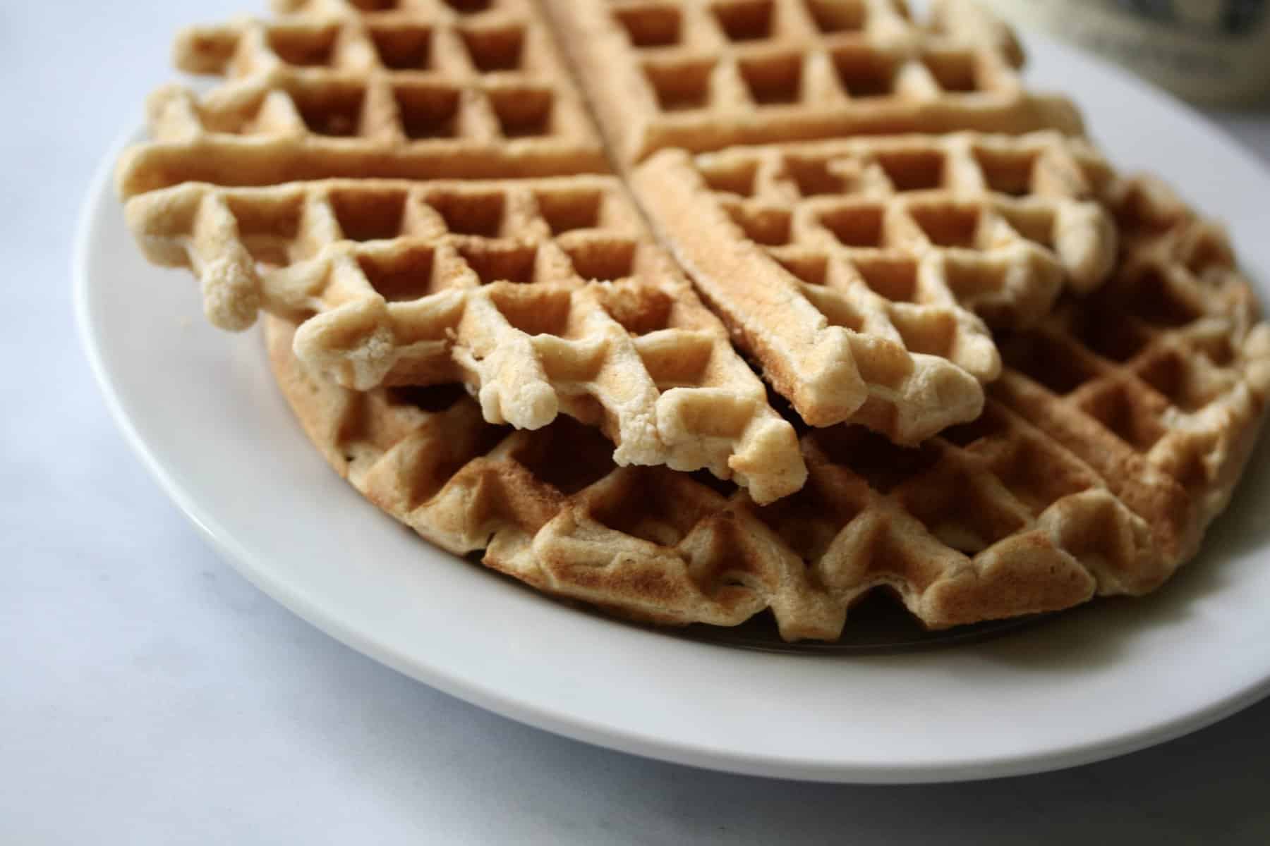 A stack of whole grain waffles on a white plate.