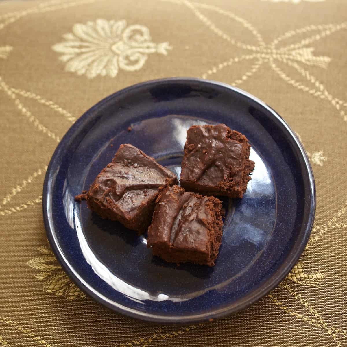 Three brownies with almond butter on a blue plate.