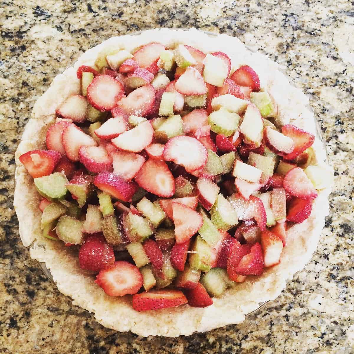The filling for strawberry rhubarb puie with honey in a pie crust.