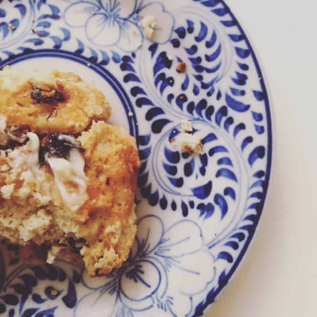 A side view of a cherry almond scone on a blue and white plate.