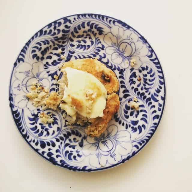 Butter tops a cherry almond scones on a blue and white plate.