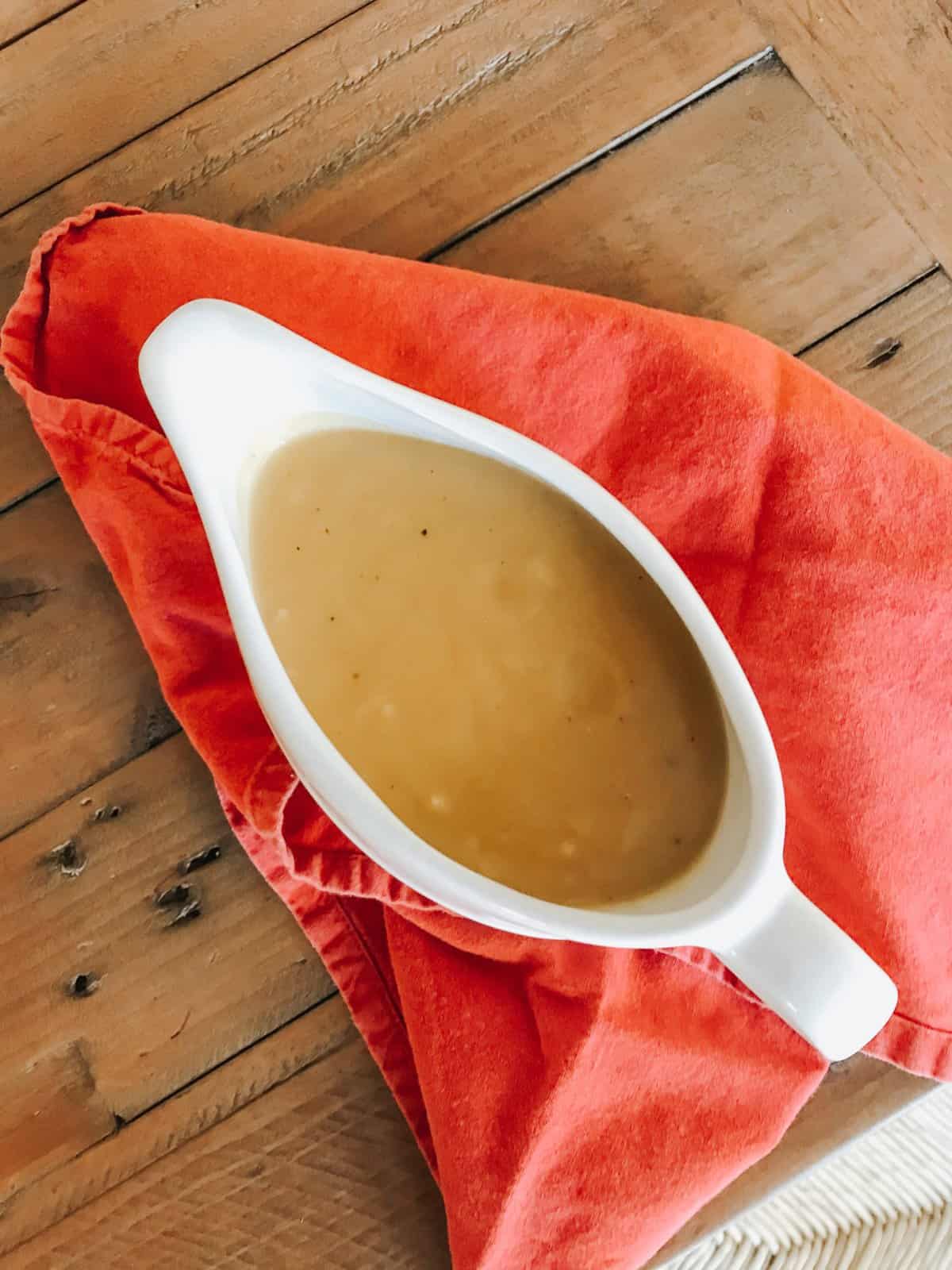 A pitcher of vegetarian gravy on a red napkin.