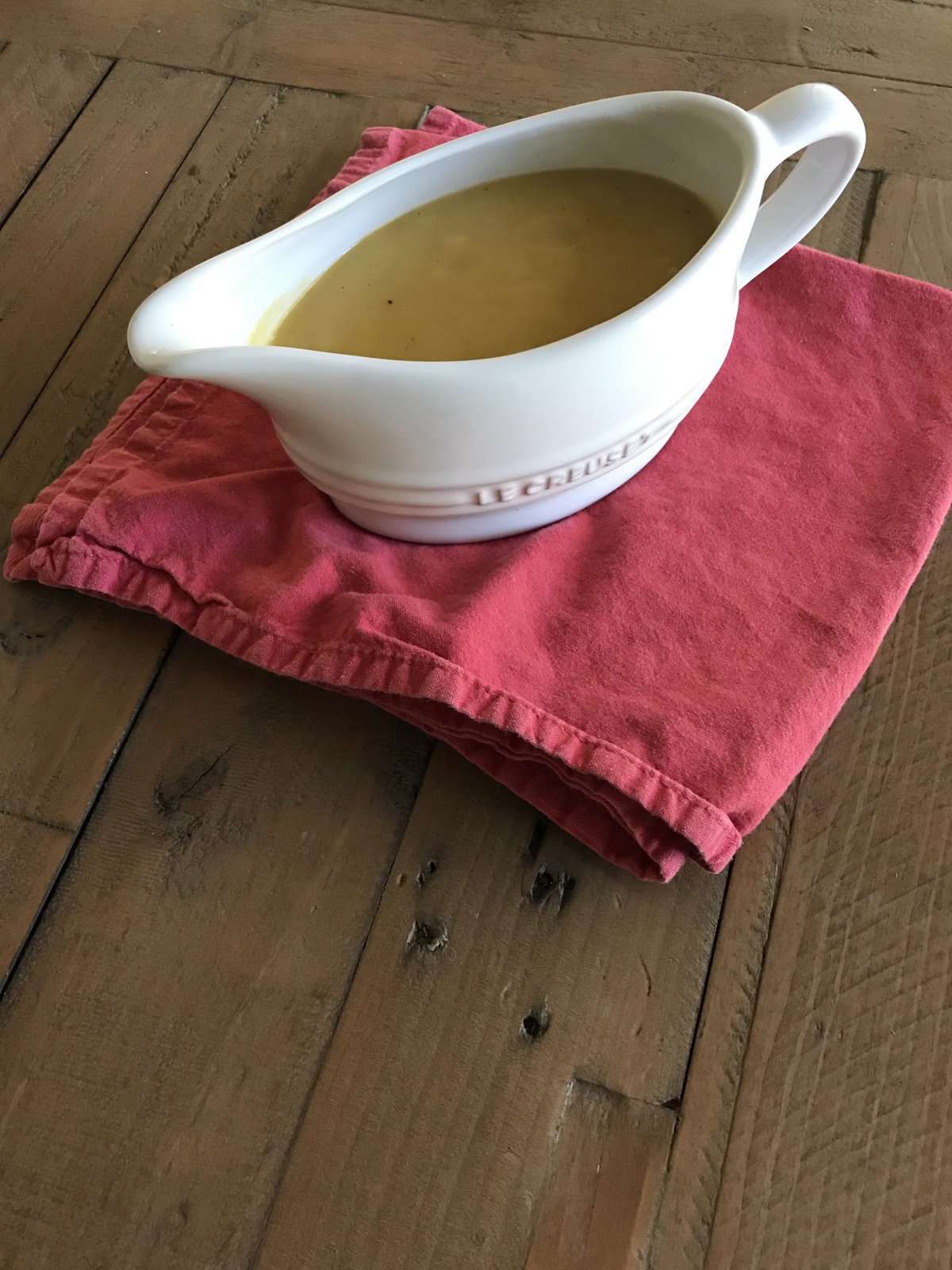 A pitcher of vegetarian gravy on a red napkin.