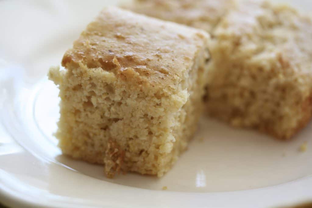 Squares of gluten free cornbread on a white plate.