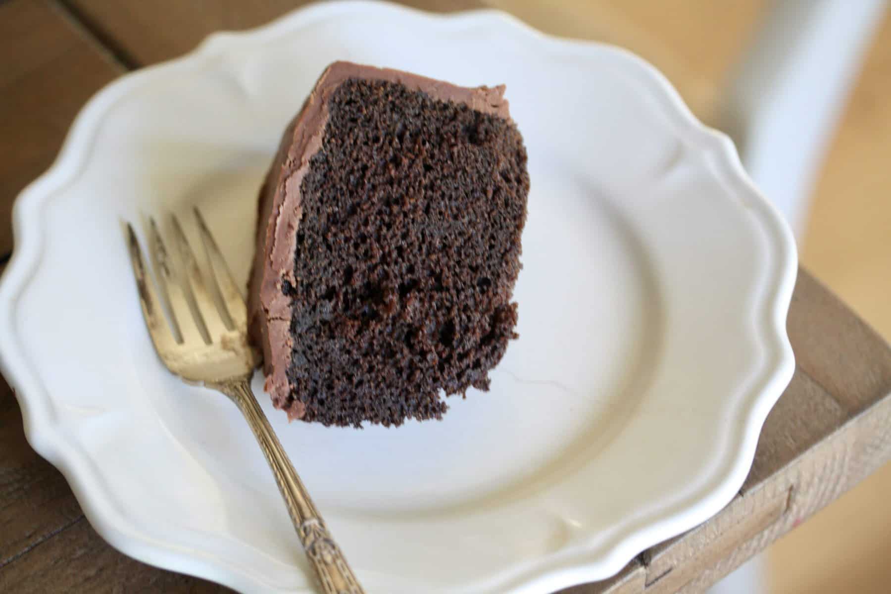 A slice of gluten free chocolate cake on a white plate.