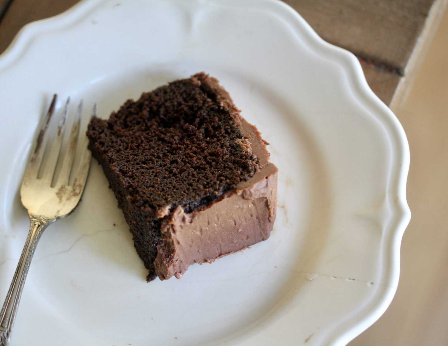 A slice of gluten free chocolate cake on a white plate.