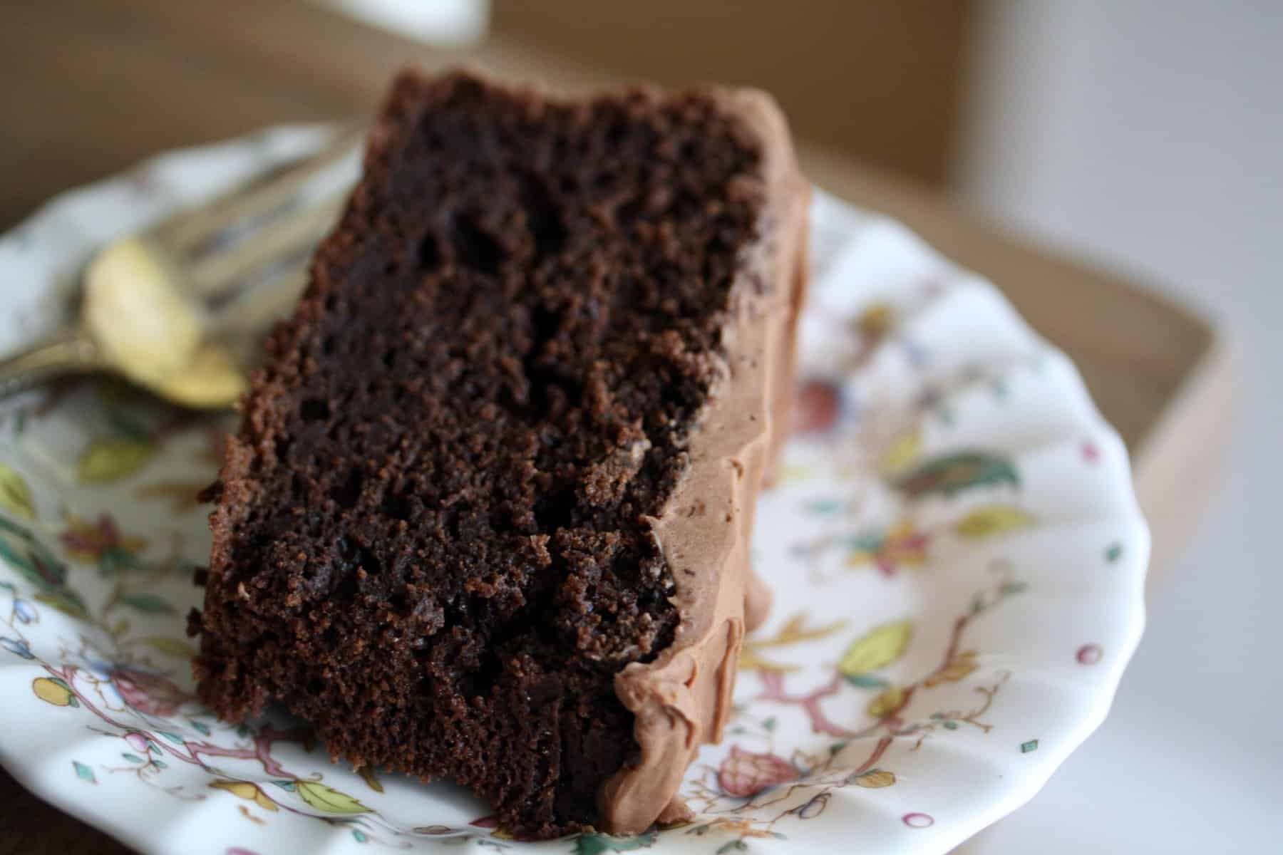 A slice of oat flour chocolate cake on a pretty plate with a fork.