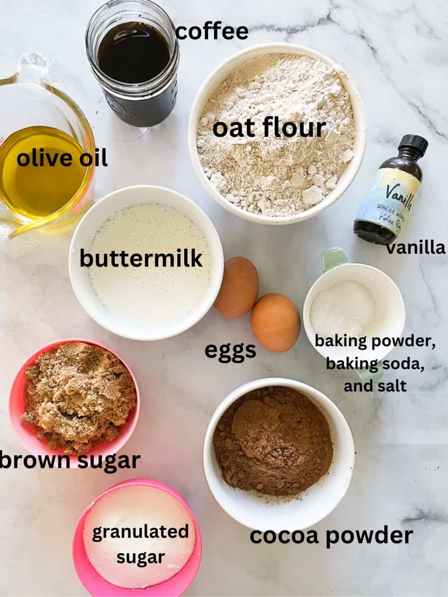 Ingredients for oat flour chocolate cake are shown and labelled: oat flour, buttermilk, brown sugar, granulated sugar, vanilla, olive oil, salt, baking powder, baking soda, eggs, vanilla, cocoa powder, coffee.