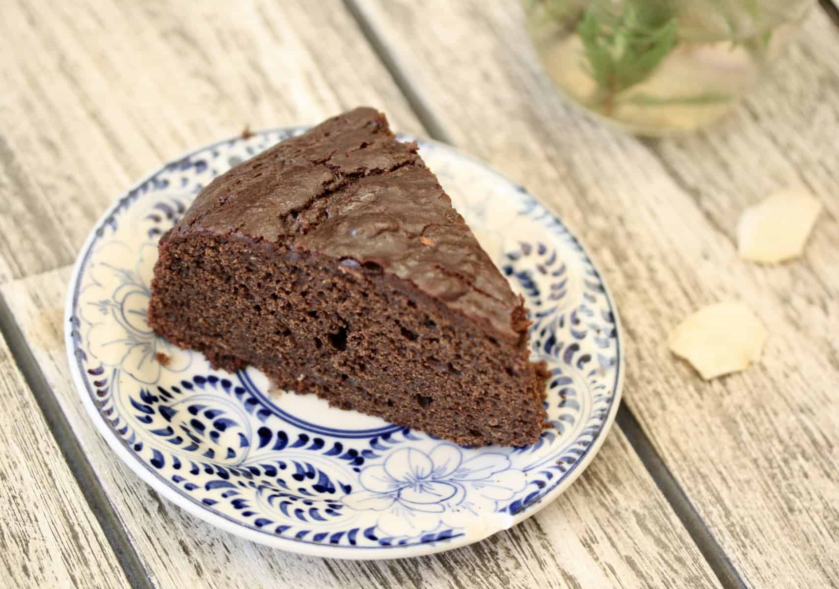 A slice of gluten-free chocolate zucchini cake on a blue and white plate.