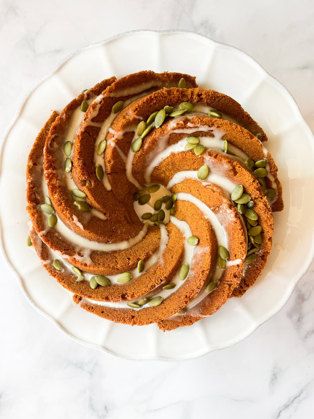 A gluten free pumpkin bundt cake topped with maple glaze and pumpkin seeds.