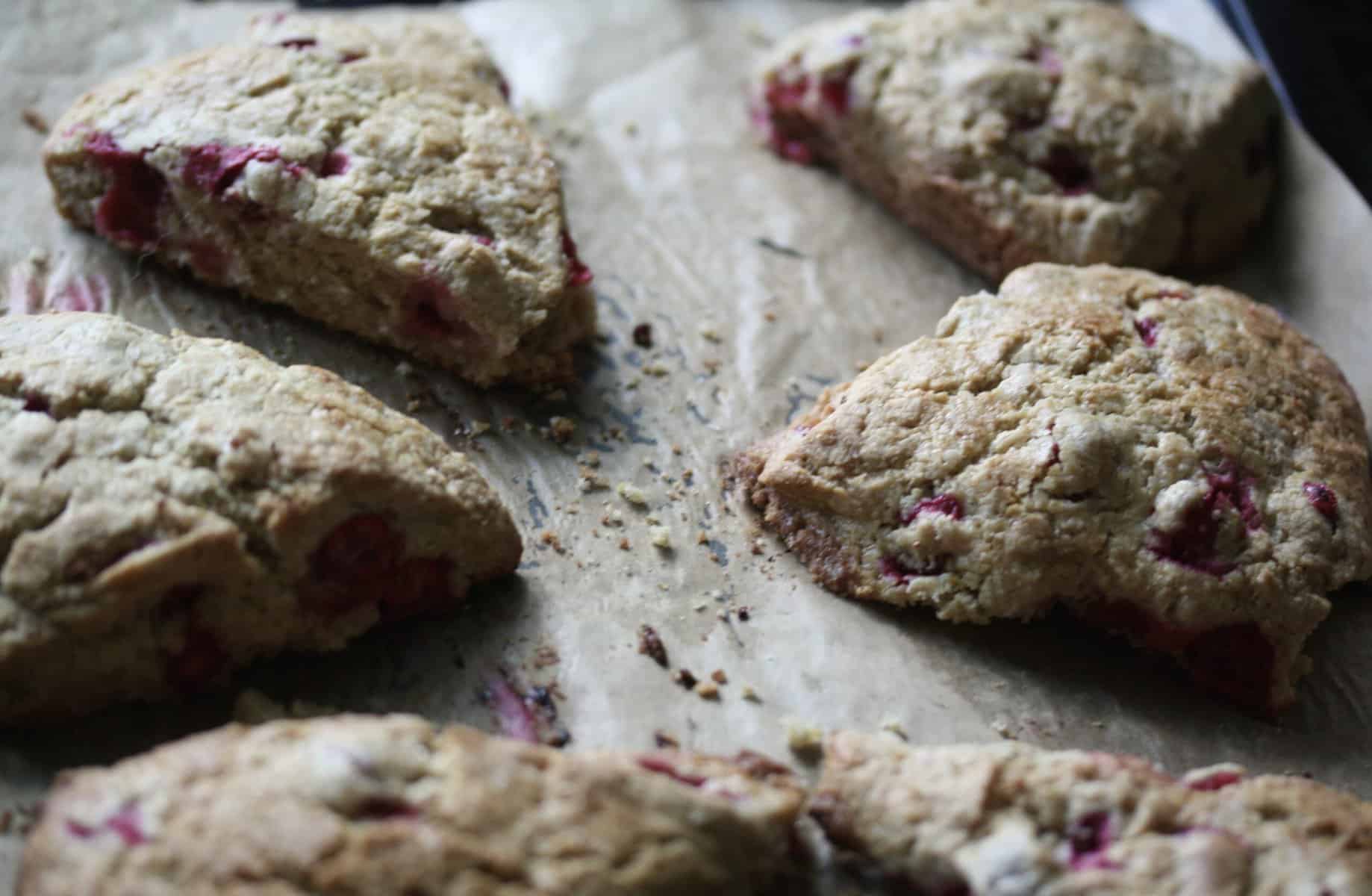 A parchment paper-lined baking sheet with cranberry scones.