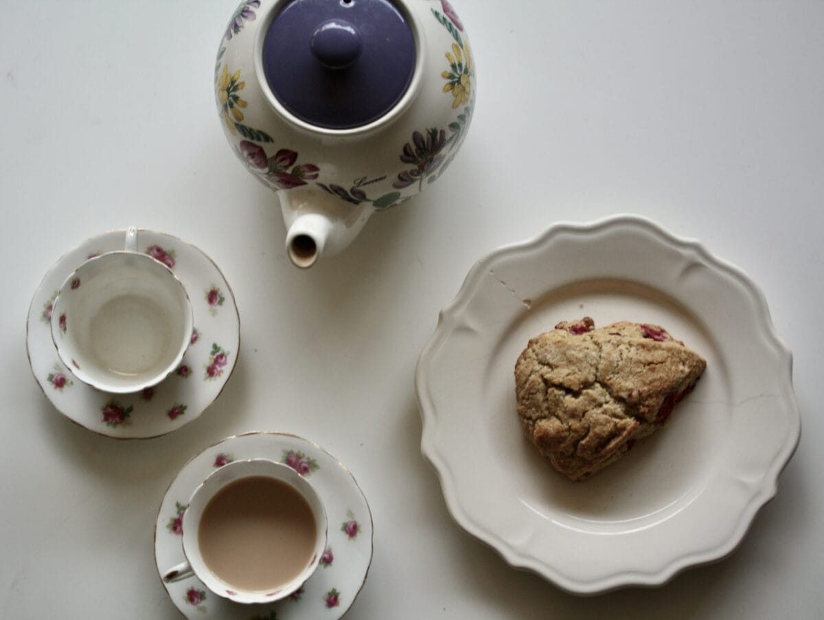 Gluten-free cranberry scones and a pot of tea with tea cups next to it.