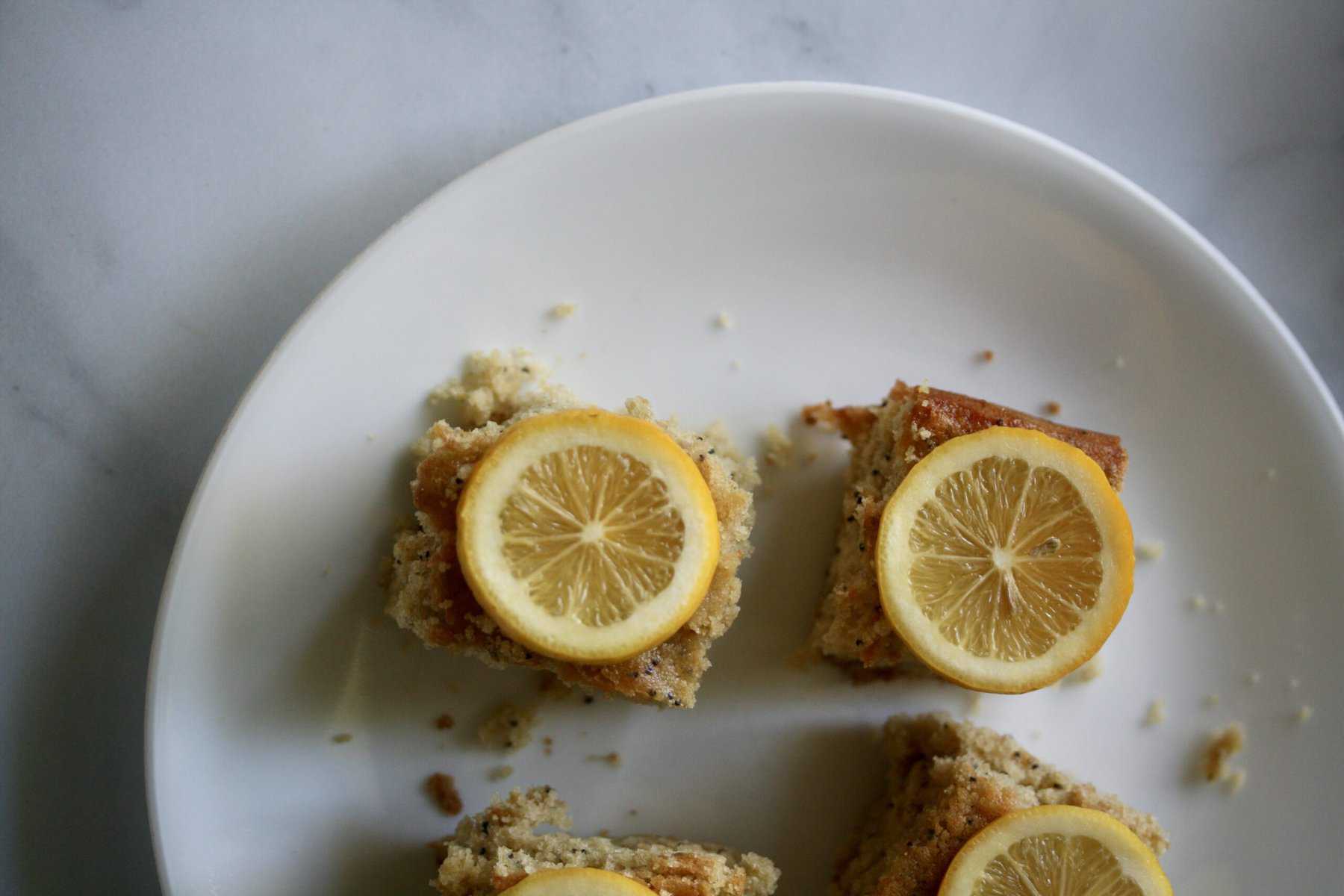 Lemon cake slices are topped with lemon.