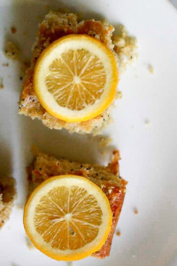 Pieces of gluten free meyer lemon snack cake topped with lemon on a plate.