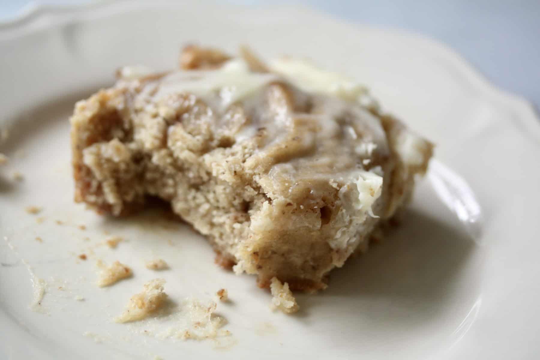 A close up of an oat flour cinnamon roll topped with cream cheese icing.