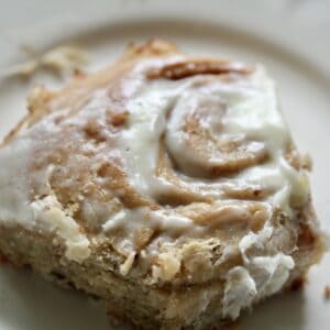A close up of an oat flour cinnamon roll topped with cream cheese icing.