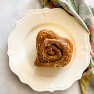 An oat flour cinnamon rolls on a plate on top of a napkin.
