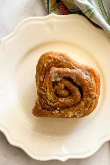 An oat flour cinnamon rolls on a plate on top of a napkin.