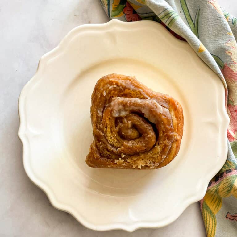 An oat flour cinnamon rolls on a plate on top of a napkin.