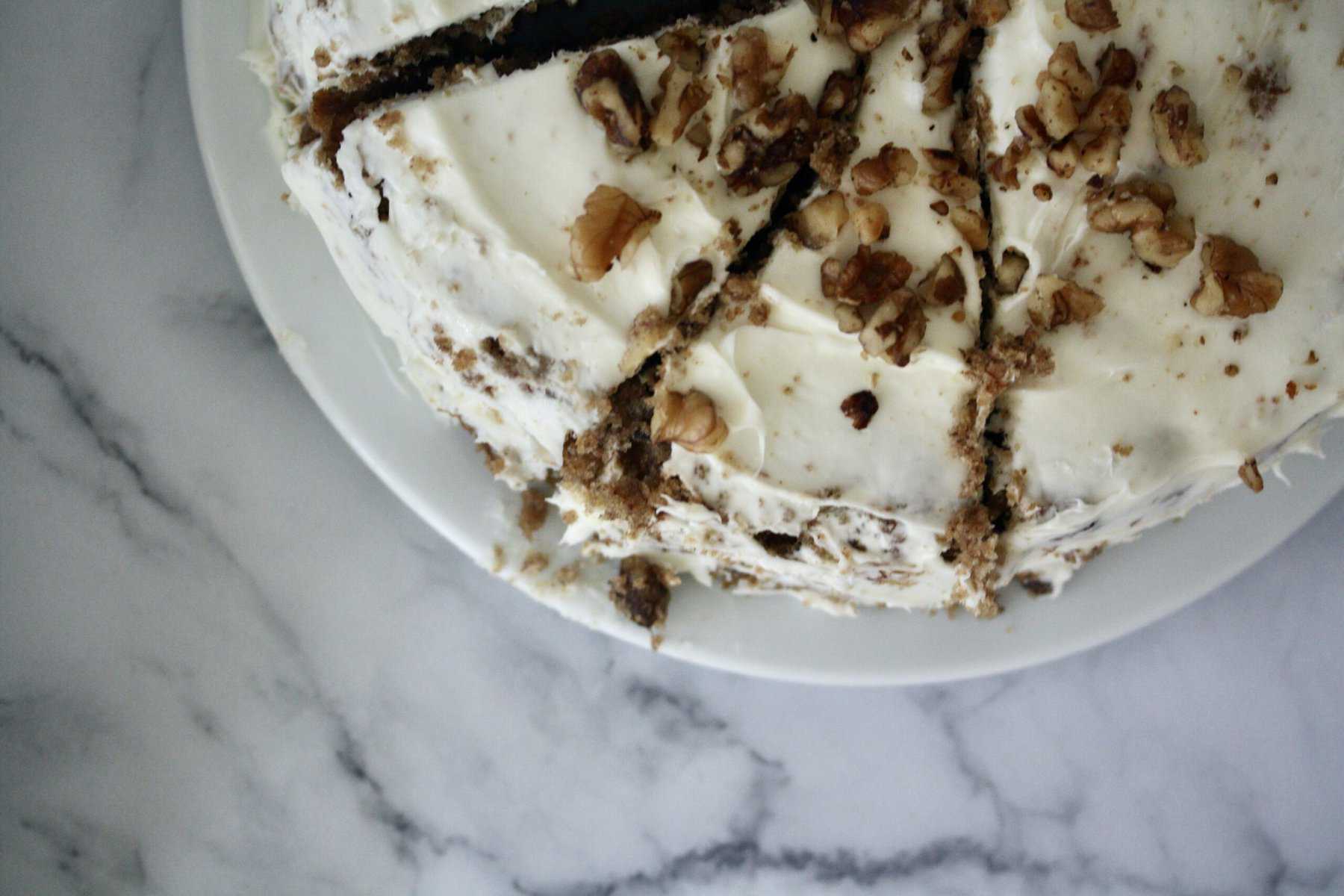 A hummingbird cake topped with toasted walnuts.
