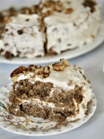 A close up of a slice of hummingbird cake with the cake in the background.