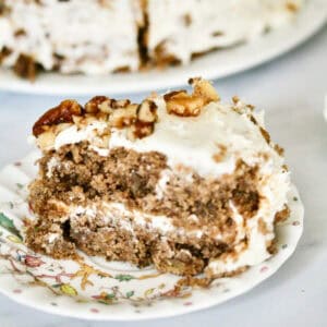 A close up of a slice of hummingbird cake with the cake in the background.