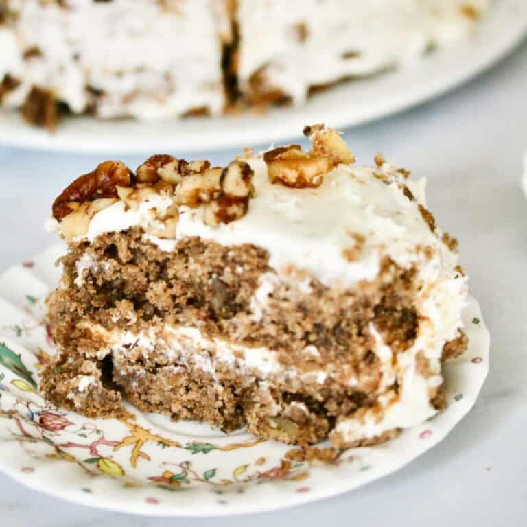 A close up of a slice of hummingbird cake with the cake in the background.