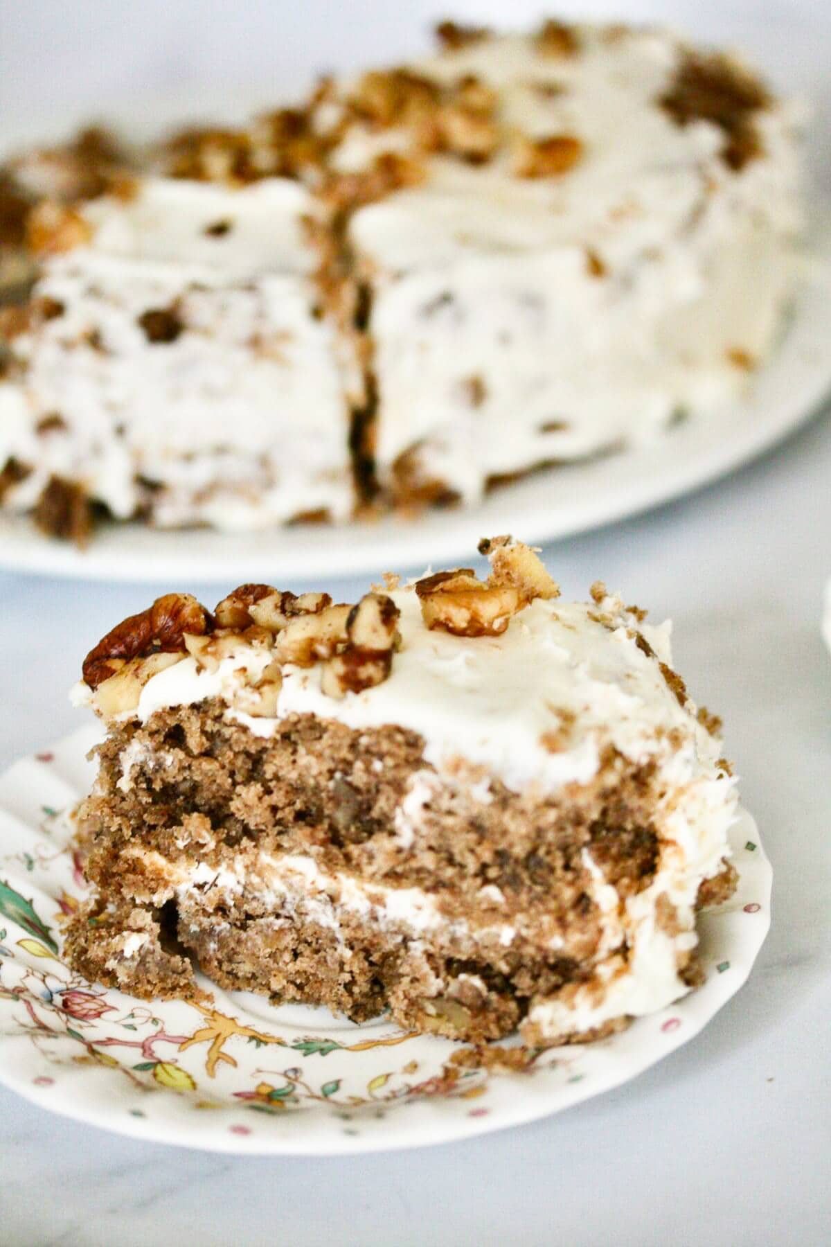 A close up of a slice of hummingbird cake with the cake in the background.