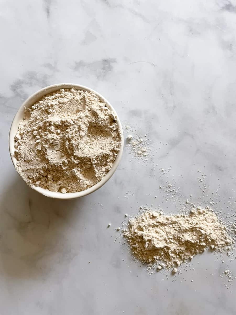 A bowl of oat flour on a white background.