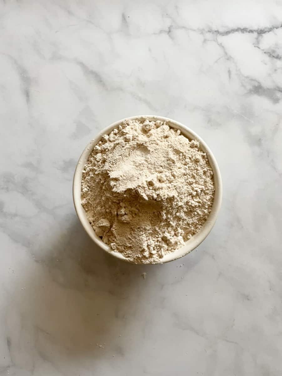 A bowl of oat flour on a white background.