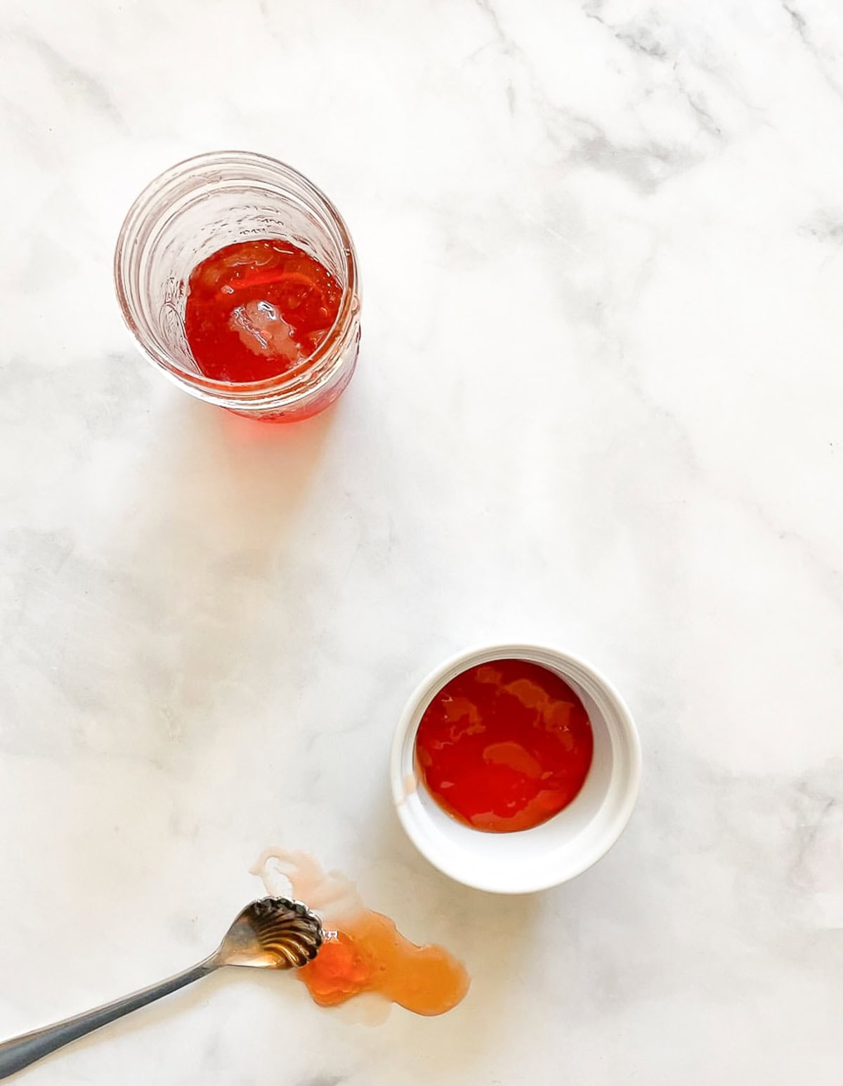 Apple jelly on a white counter with a spoon.