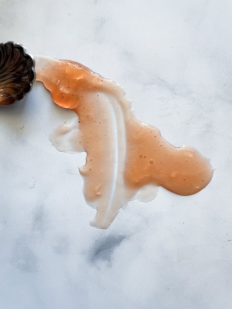 A spoon and a smear of apple jelly on a white background.