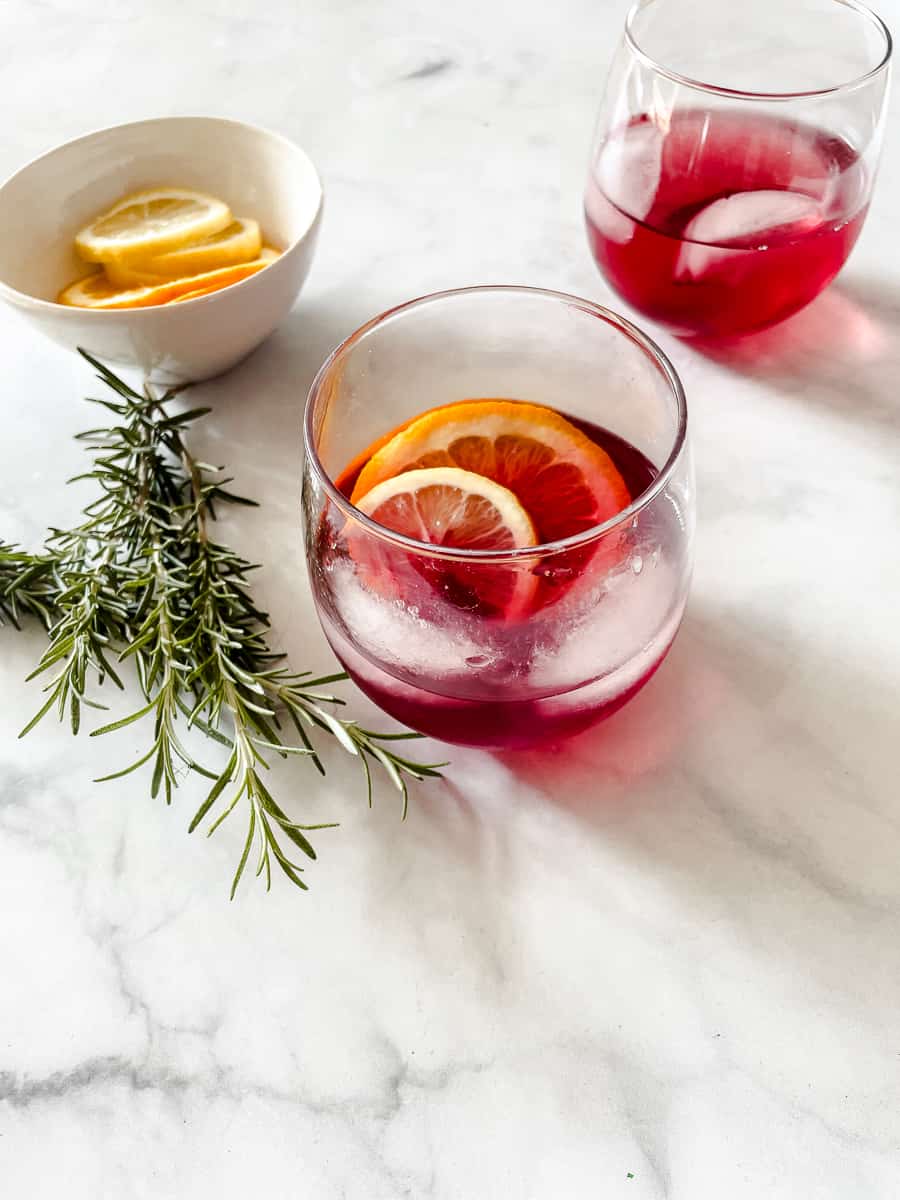 Glasses of cranberry margarita on a white background with fresh rosemary.