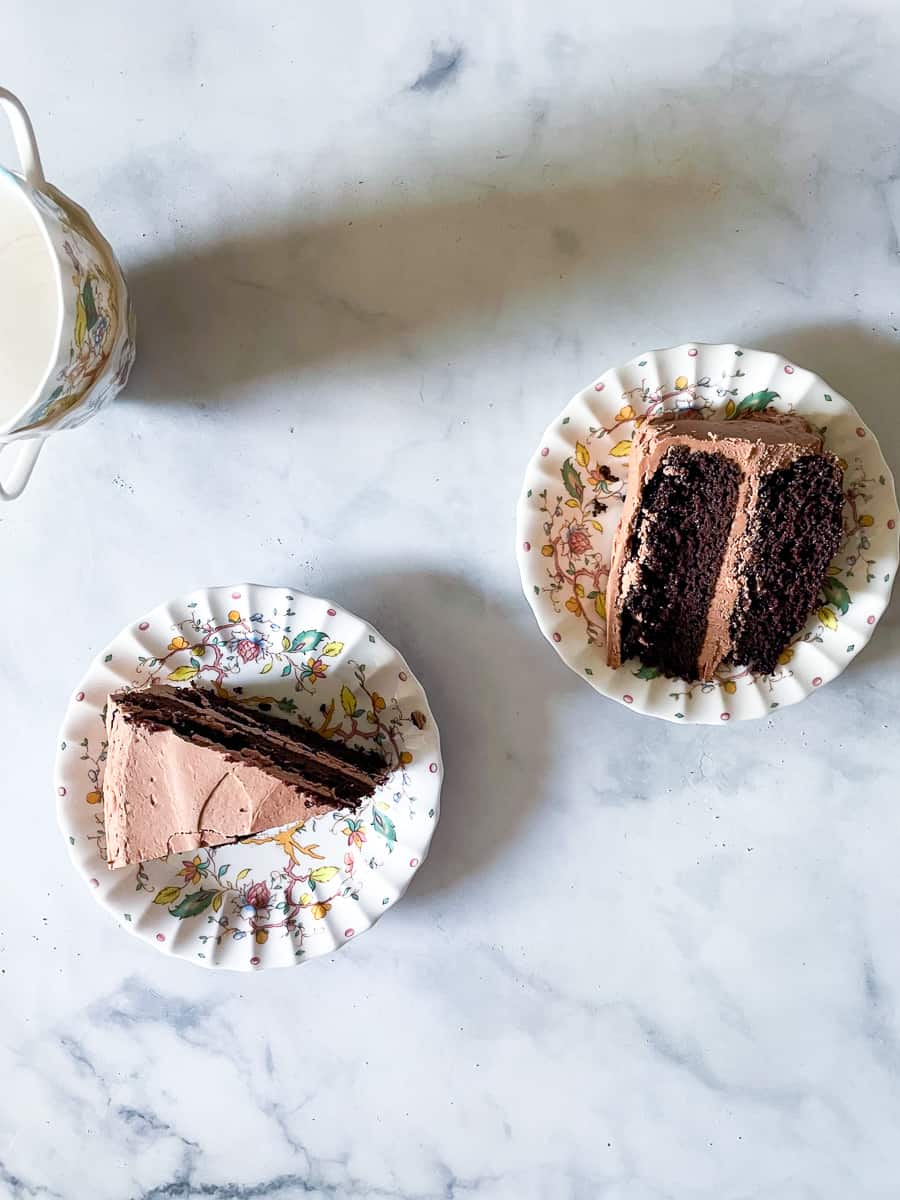 Two slices of chocolate layer cake on plates.