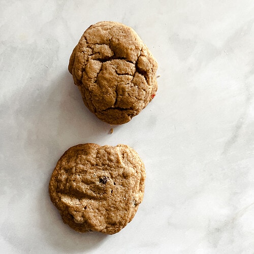 Two whole wheat chocolate chip cookies on a white background.
