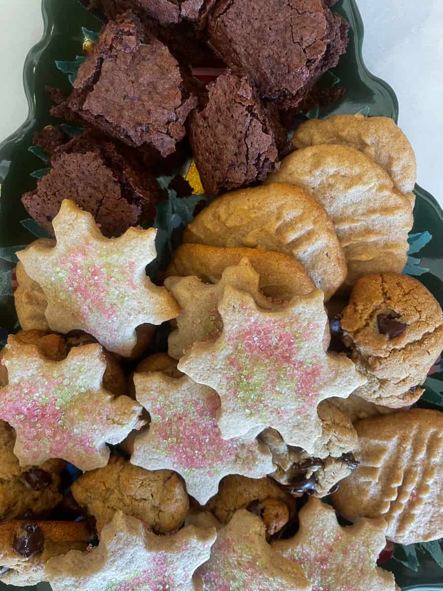 A gluten free Christmas cookie plate with gluten free sugar cookies, peanut butter cookies, almond flour chocolate chip cookies, and gluten free brownies.