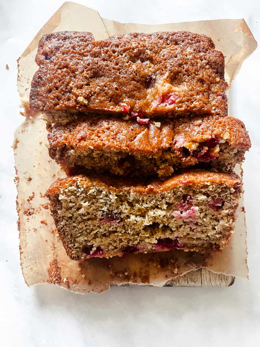 Thick slices of cranberry orange bread on a piece of parchment paper.