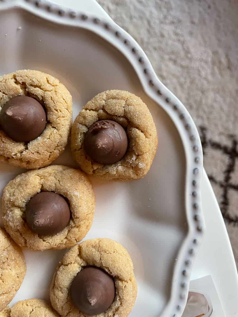 A side view of a plate of Hershey's kisses-topped gluten free peanut butter blossoms.