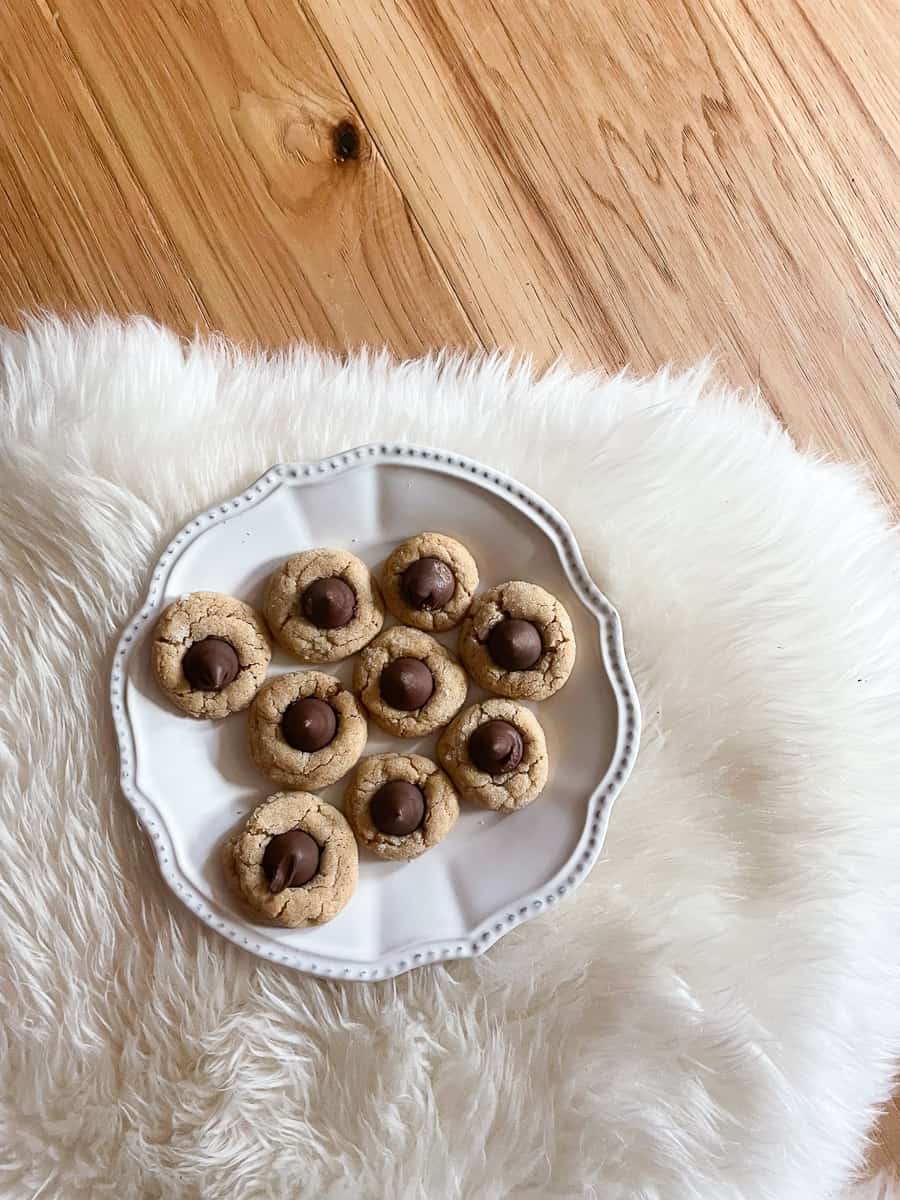 A plate of gluten free peanut butter blossoms on a white cozy rug,