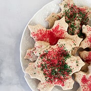 A side view of a plate of red and green sprinkle-topped oat flour sugar cookies.