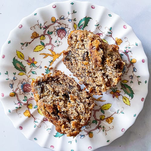 A flowered plate holds two halves of an oat flour banana muffin.